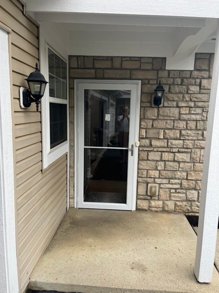 Dark full-view storm door at a stone and siding porch